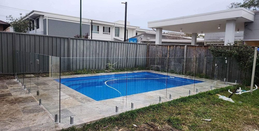 A Large Swimming Pool Surrounded by a Glass Fence in a Backyard — Cessnock Glass in Cessnock, NSW