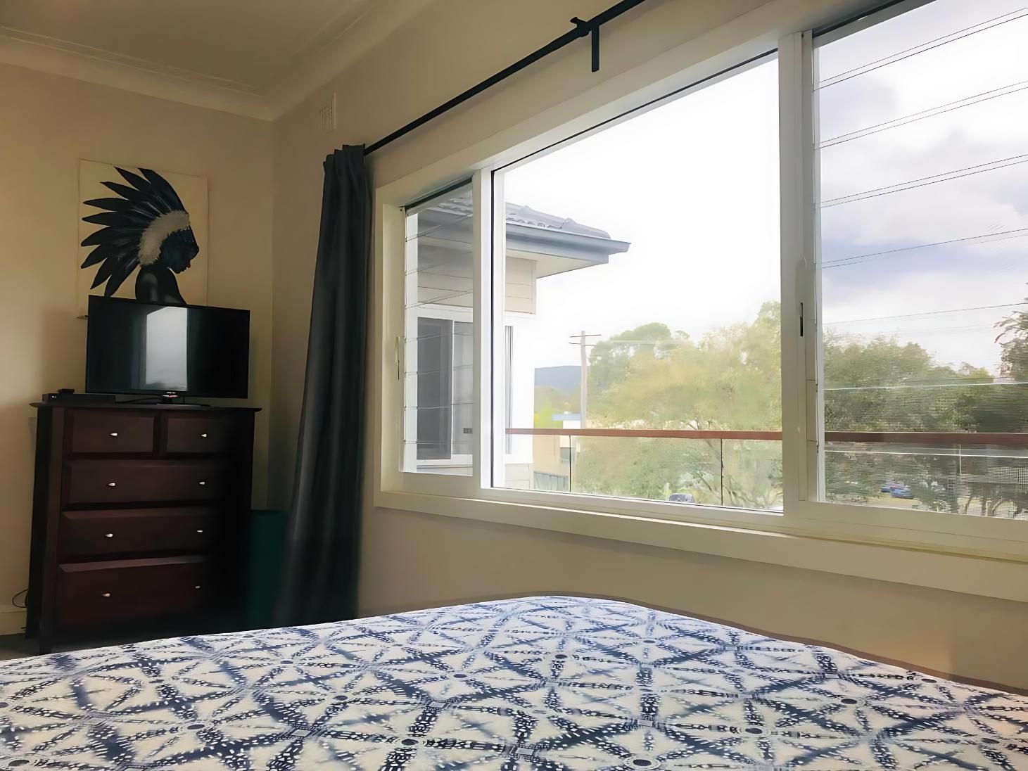 A Bedroom With a Bed , Dresser, Television and a Large Window — Cessnock Glass in Port Stephens, NSW