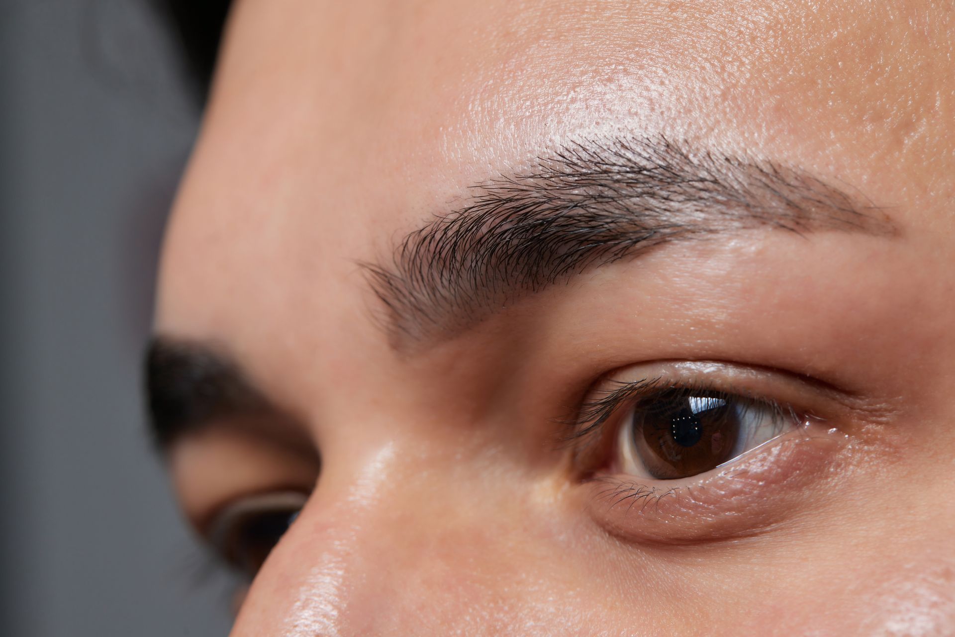 Close-up of a person's eye and eyebrow. The eyebrow is dark and defined; the eye is brown and open.