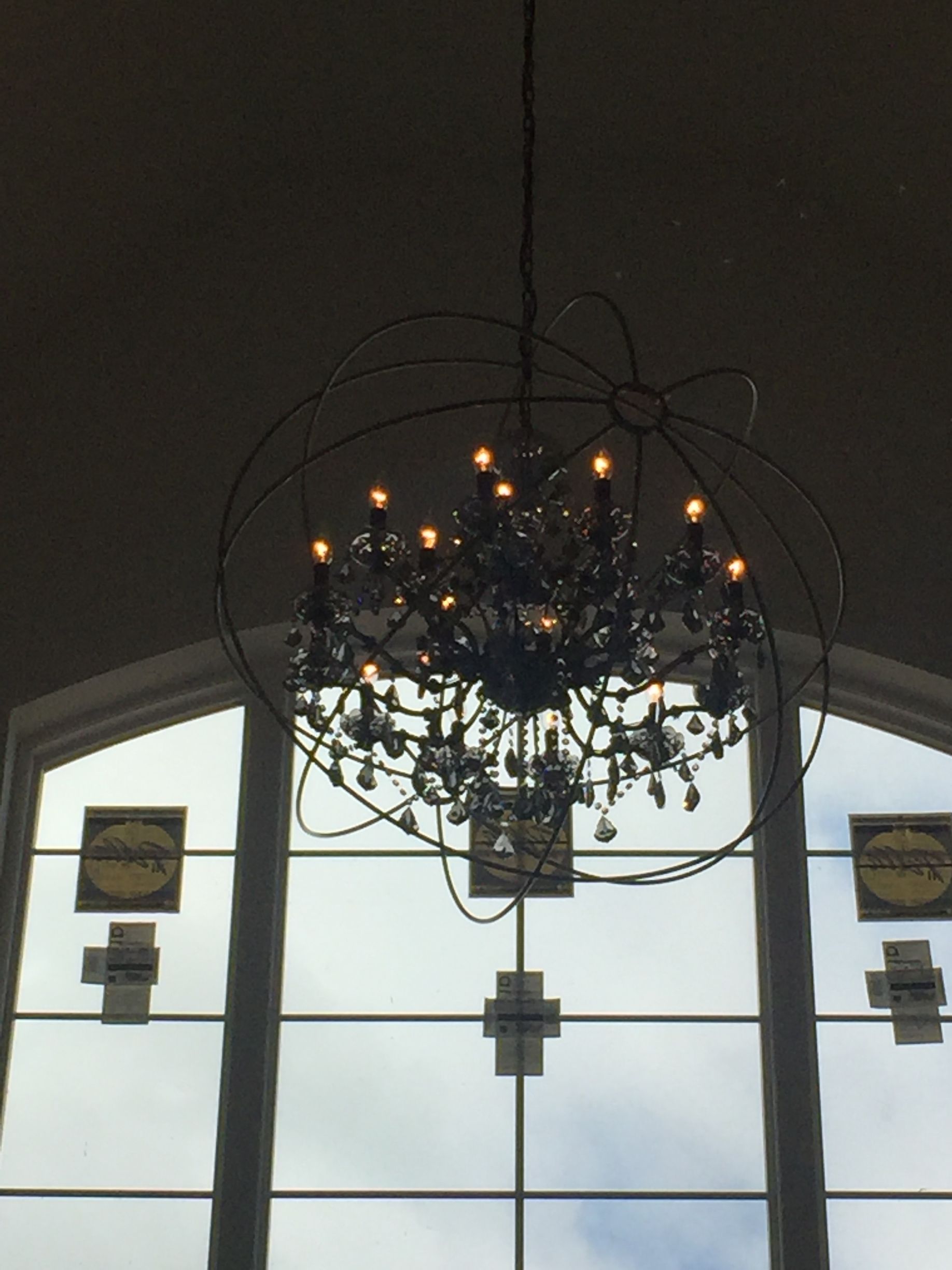 A chandelier is hanging from the ceiling in front of a window