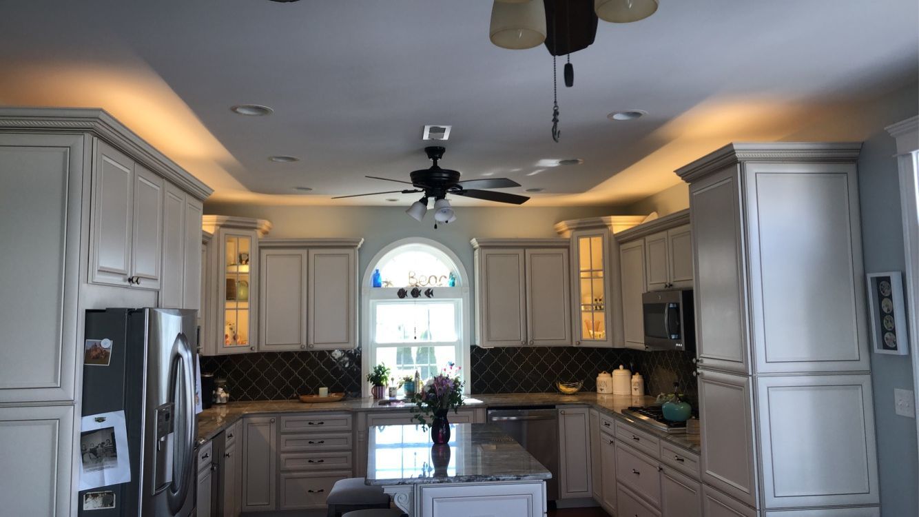 A kitchen with white cabinets and a ceiling fan