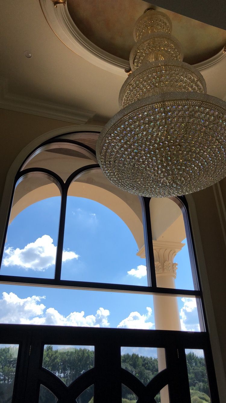 A large chandelier is hanging from the ceiling above a window.