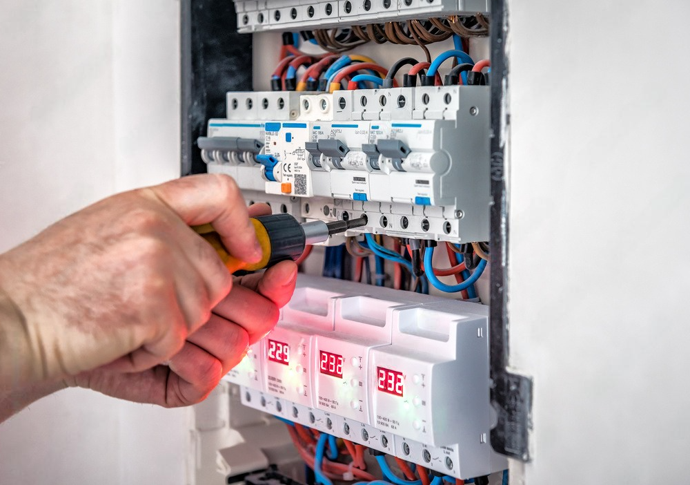 a person is working on an electrical box with a screwdriver .