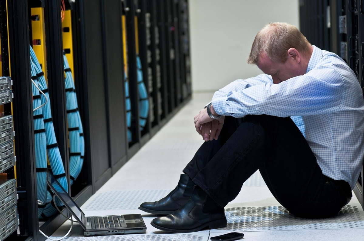 Image of a man looking upset in a server room by no backup plan