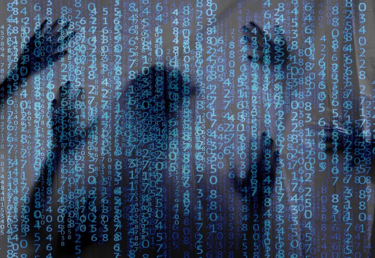 Image of computer code with a shadowy person behind