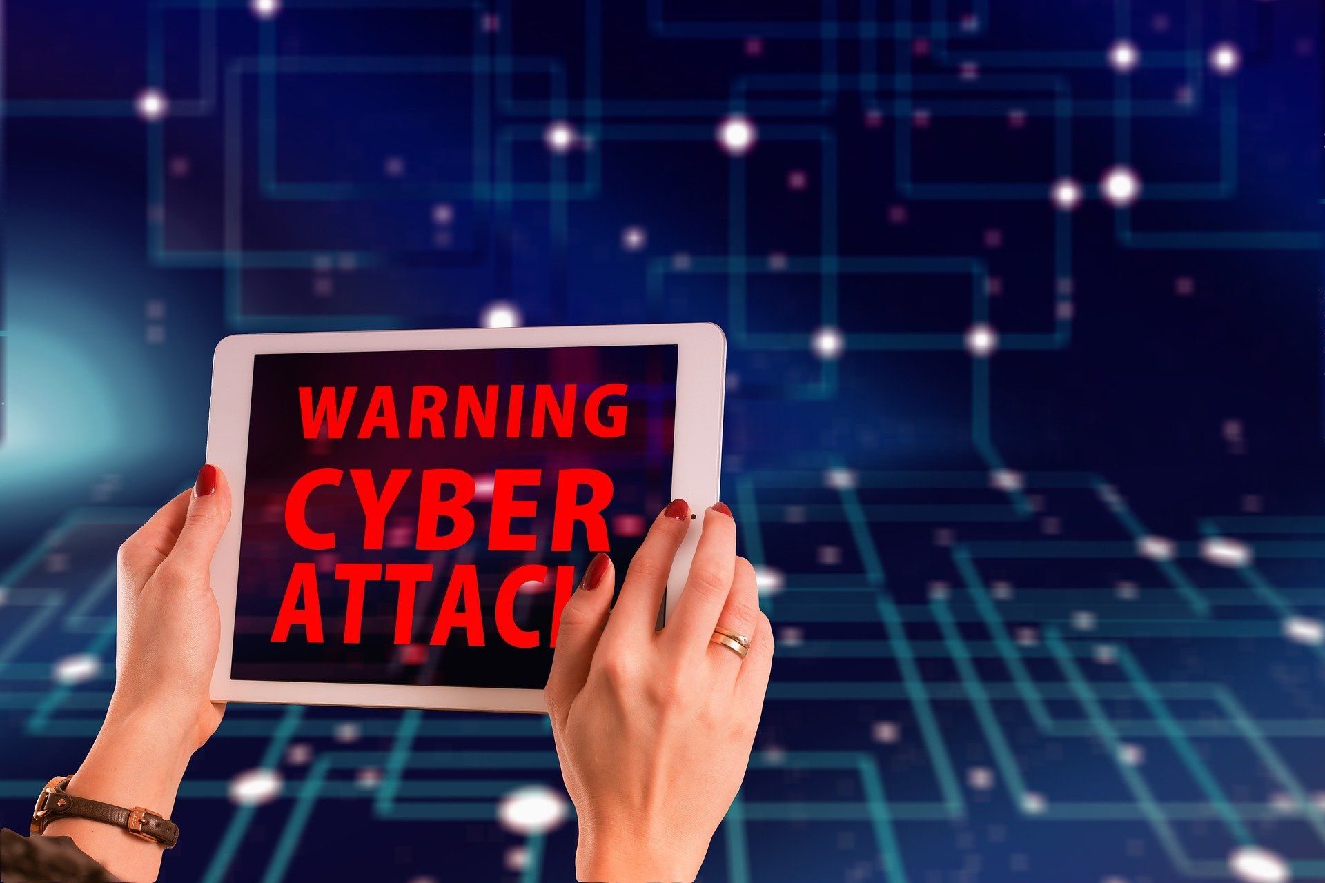 Image of someone holding up a tablet that says warning cyber attack