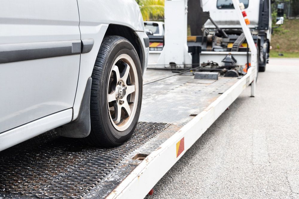 Cable attached to broken down car being pulled onto flatbed tow truck — Traffic Solicitors in Muswellbrook NSW