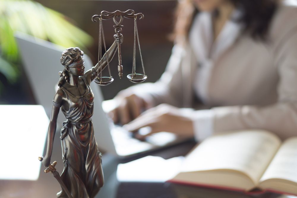 Statue of Justice with scales and lawyer working on a laptop — Solicitors in Port Stephens, NSW