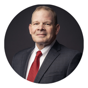 A man in a blue suit and white shirt is smiling in a circle.