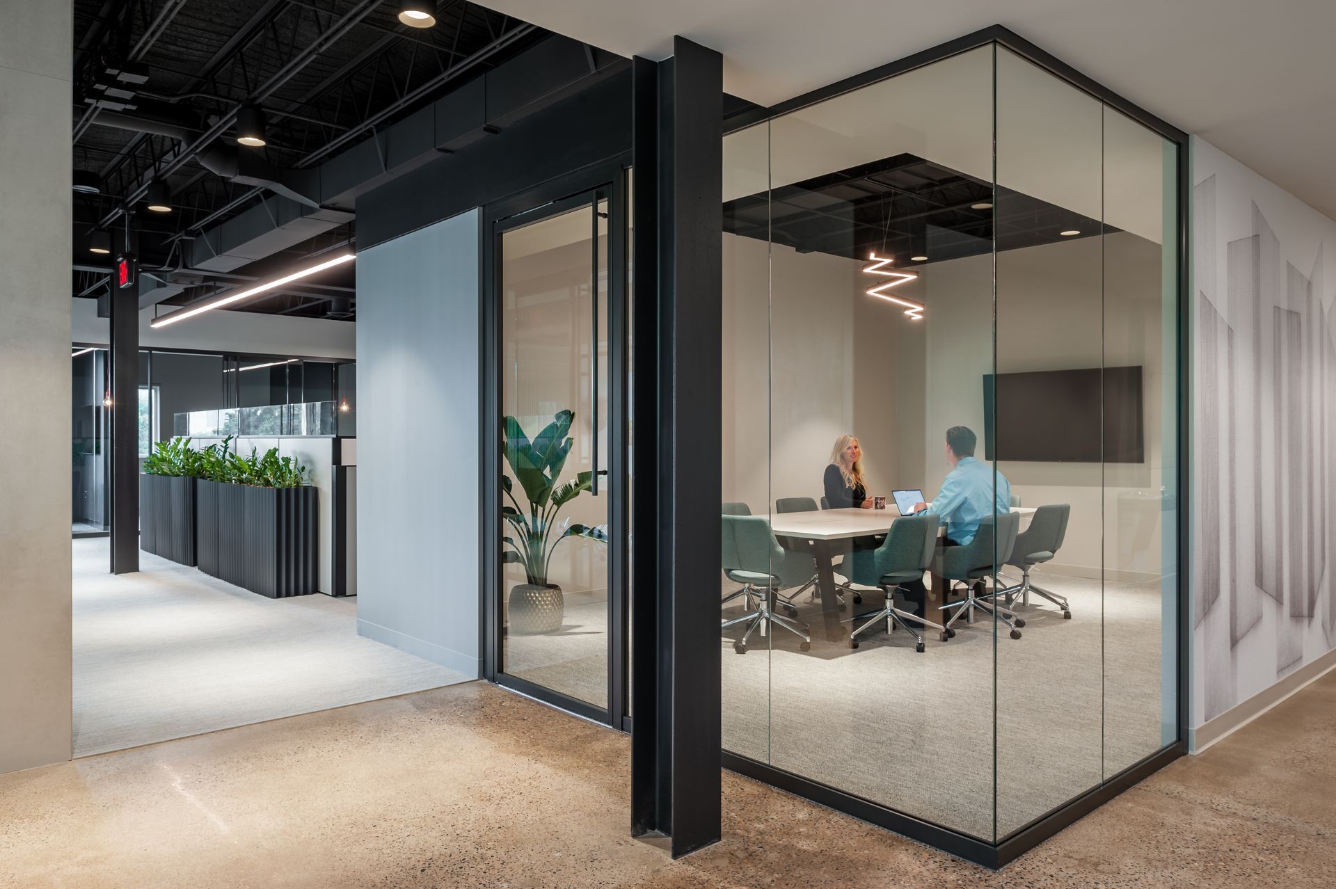 A couple of people are sitting at a table in a conference room.