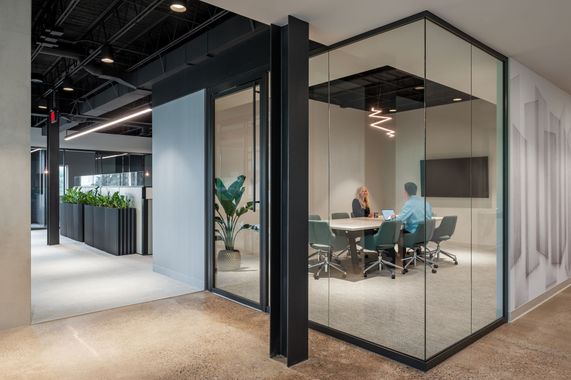 A couple of people are sitting at a table in a conference room.