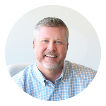 A man with a beard and a plaid shirt is smiling in a circle.