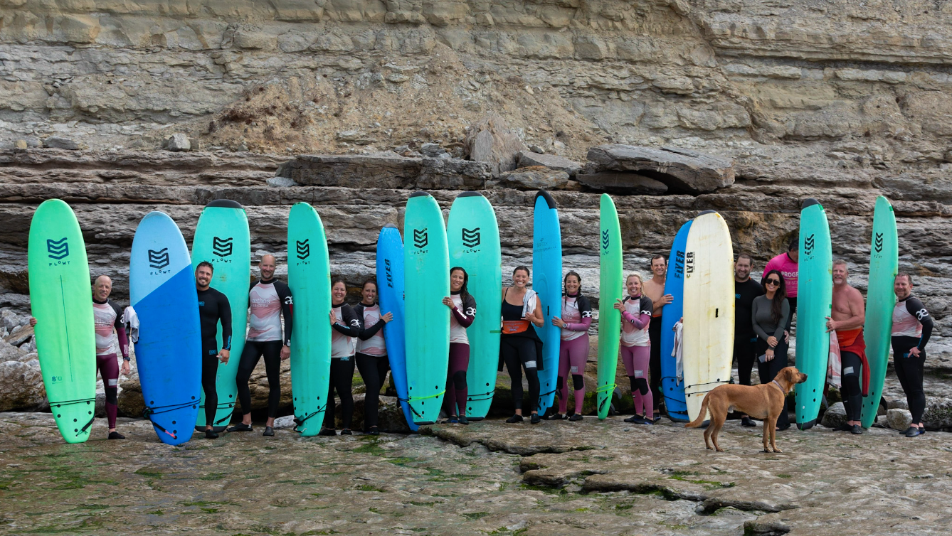 Three people smiling at sunset in a vineyard; man with arms around women's shoulders.