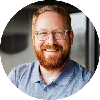 A man with a beard wearing glasses and a blue shirt