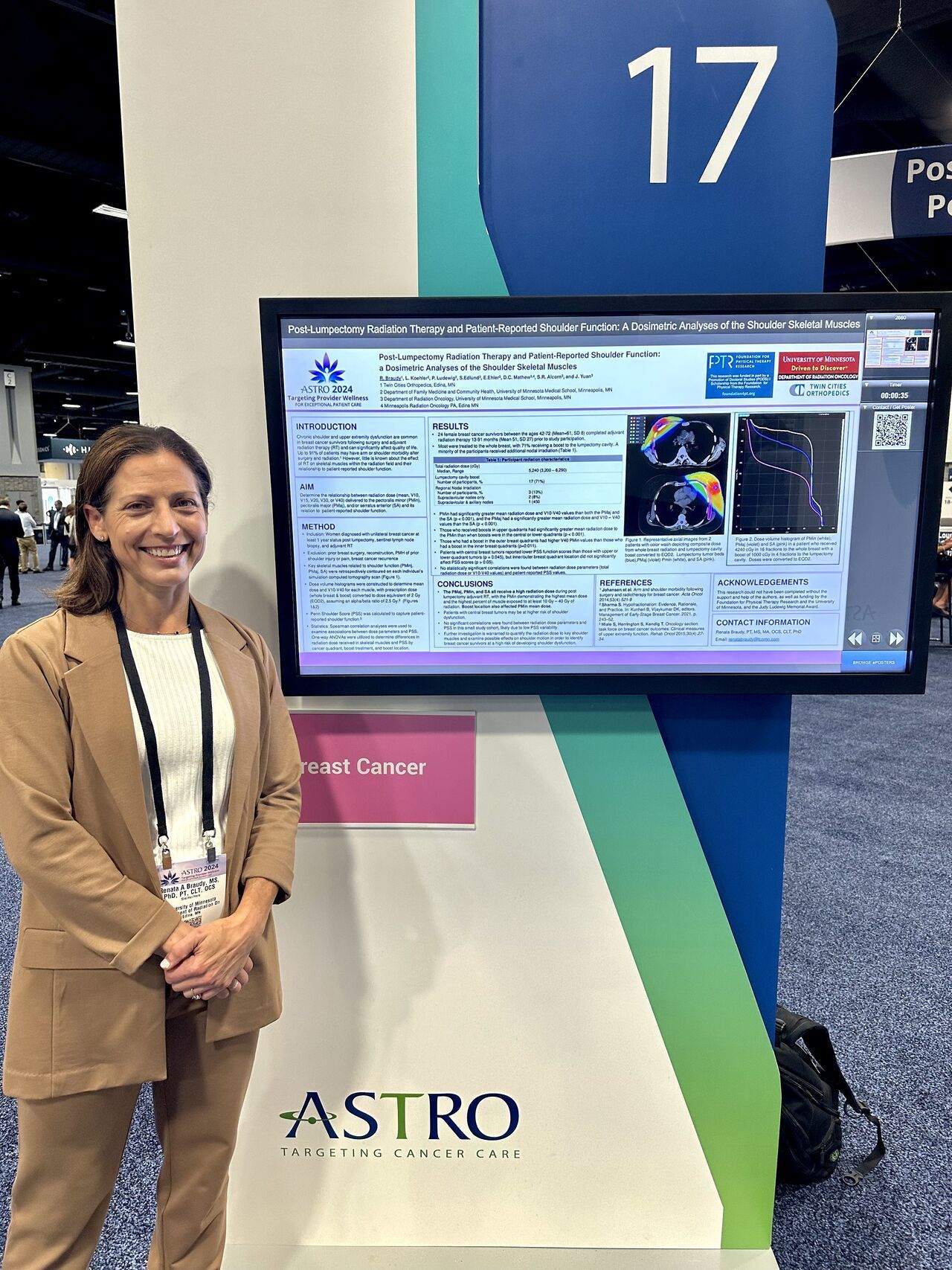Woman stands by a presentation screen at an ASTRO conference, wearing a tan suit, smiling.