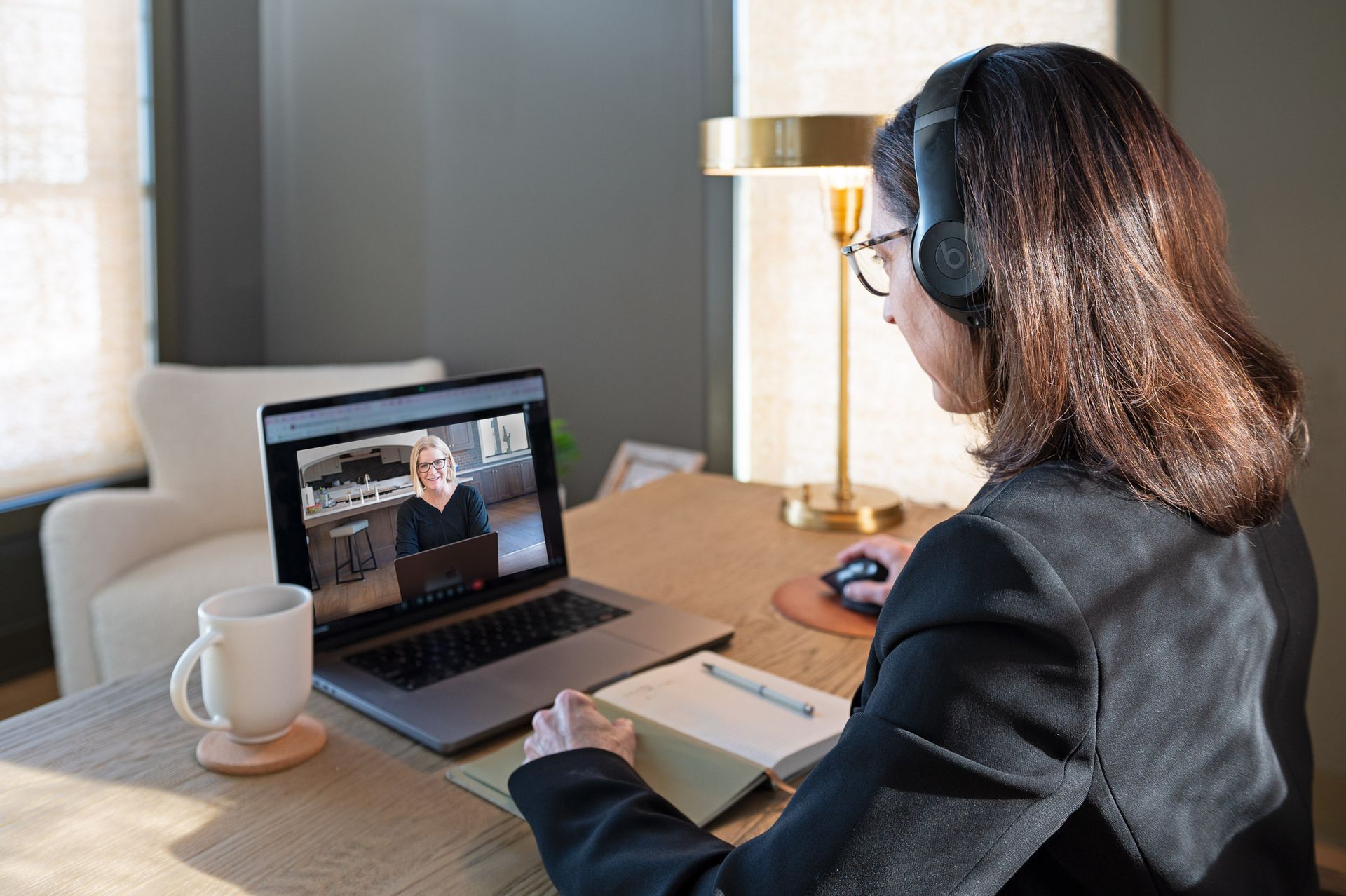 Three women pose together. Two wear blazers; one embraces the others. All wear lanyards. Indoors, conference setting.