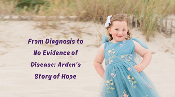 A little girl in a blue dress is standing on a sandy beach.