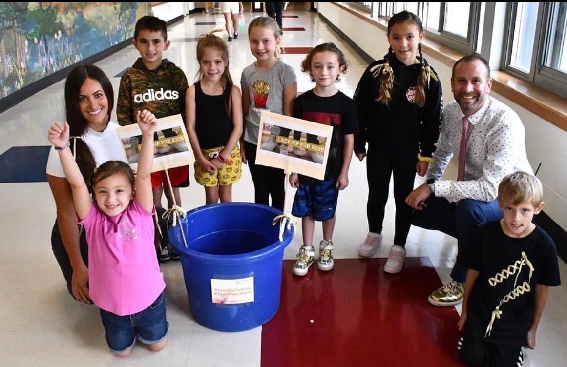 A group of children are posing for a picture in a hallway.