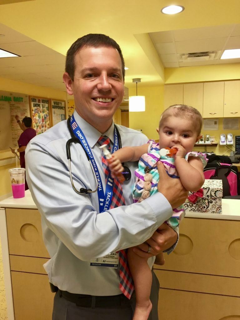 A doctor is holding a baby in his arms in a hospital room.