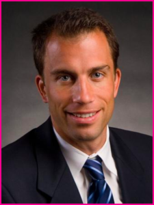 A man in a suit and tie smiles for the camera