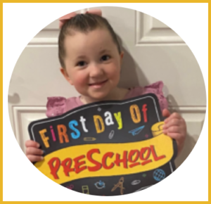 A little girl is holding a sign that says first day of preschool