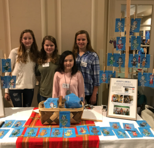 A group of girls are posing for a picture in front of a table