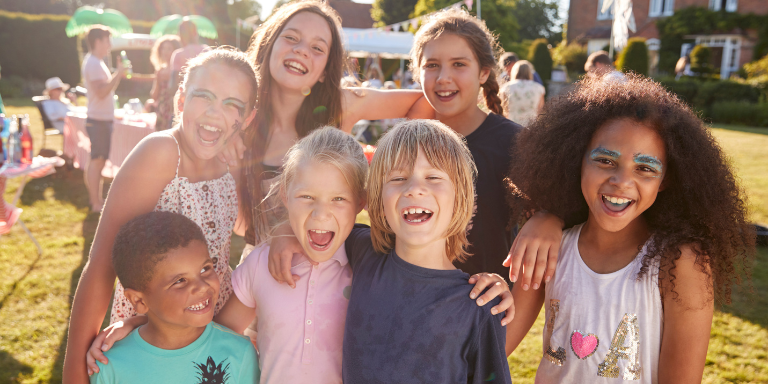 A group of children are posing for a picture together in a park.