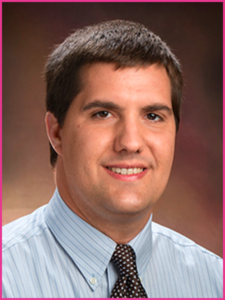 A man in a striped shirt and tie smiles for the camera