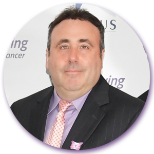 A man in a suit and tie stands in front of a sign that says ing on it