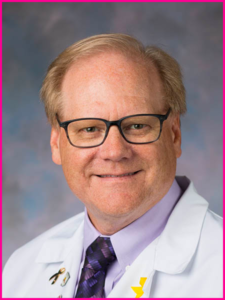 A man wearing glasses and a white coat and tie