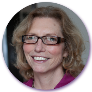 A woman wearing glasses and a purple shirt smiles for the camera