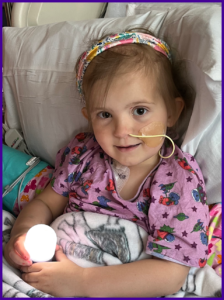 A little girl in a hospital bed holding a light bulb