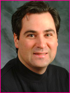 A man in a black turtleneck smiles for the camera
