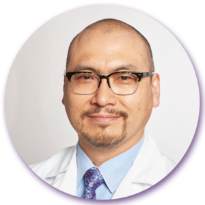 A man with glasses and a beard is wearing a white coat and tie