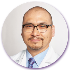 A man with glasses and a beard is wearing a white coat and tie