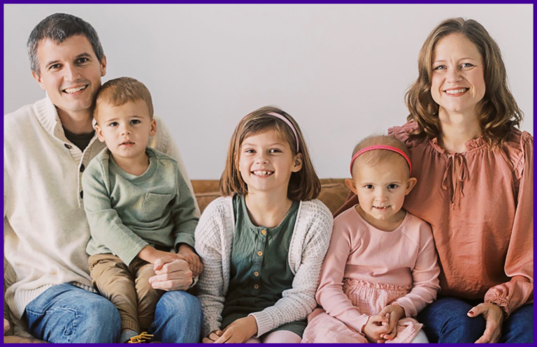 A family is posing for a picture while sitting on a couch.