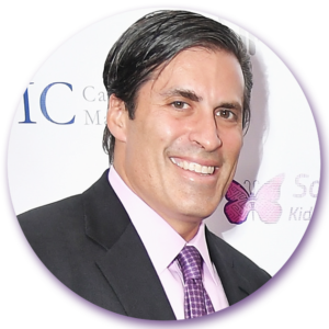 A man in a suit and tie is smiling in front of an ic logo