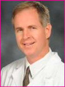 A man in a white coat and tie is smiling for the camera.