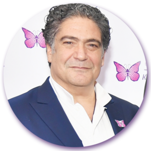 A man in a suit stands in front of two pink butterflies