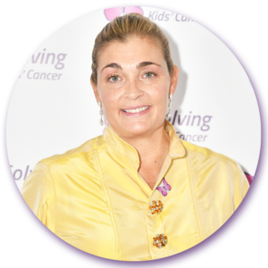 A woman in a yellow shirt is smiling in front of a sign that says living cancer