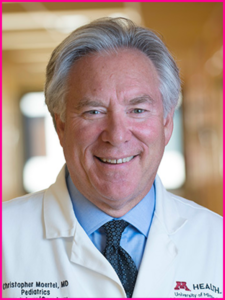 A man in a white coat with the name christopher moertel on it