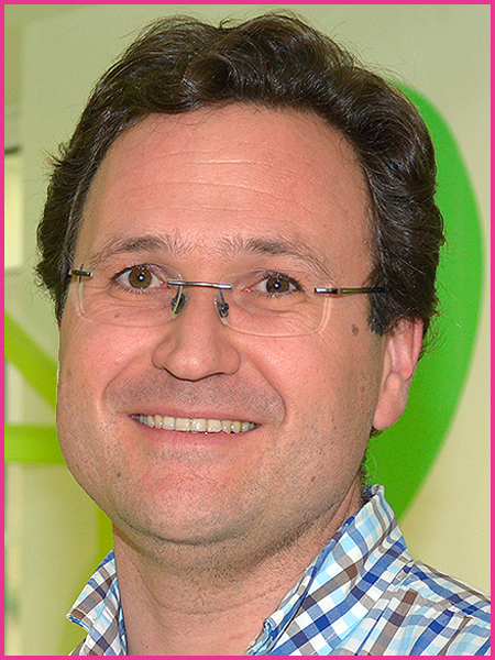 A man wearing glasses and a plaid shirt is smiling