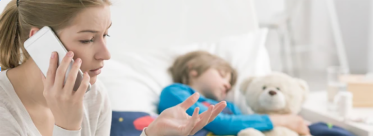 A woman is talking on a cell phone while a child is sleeping in a bed.