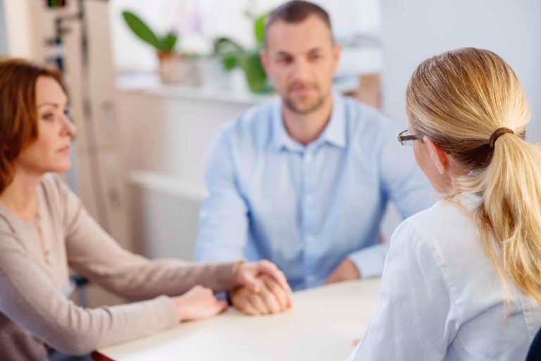 A man and a woman are sitting at a table talking to a doctor.