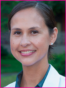 A woman in a white lab coat is smiling for the camera