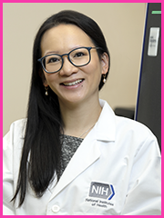 A woman wearing glasses and a lab coat with the word nih on it