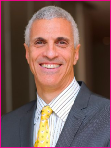 A man in a suit and tie smiles for the camera