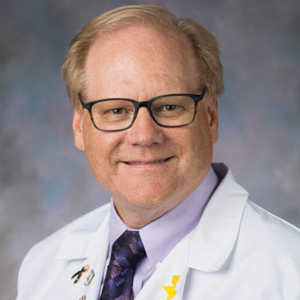 A man wearing glasses and a white coat and tie