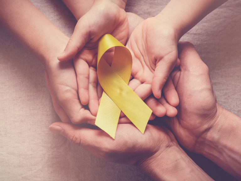 A group of people are holding a yellow ribbon in their hands.