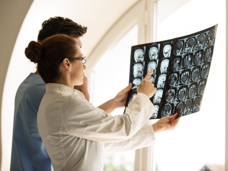 A man and a woman are looking at an x-ray of a person 's head.